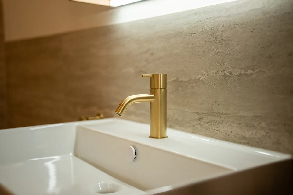 Einzelwaschbecken mit goldfarbener Armatur im Arvion-Showroom